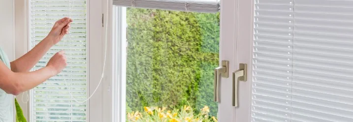 Person justiert Jalousie an Terrassentür